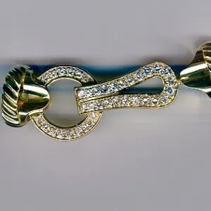 A close up of the gold and diamond clasp on a bracelet.