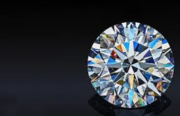 A sparkling round-cut diamond on a black surface.